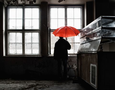 Mężczyzna mienia czerwony parasol otwarty wśrodku budynku