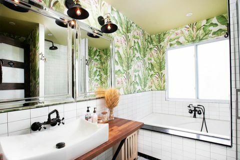 łazienka z tapetą botaniczną, wanną, umywalką i oświetleniem