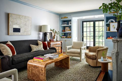 salon z czarną sofą, drewniany stolik kawowy z książkami, ściany pomalowane na jasnoniebiesko