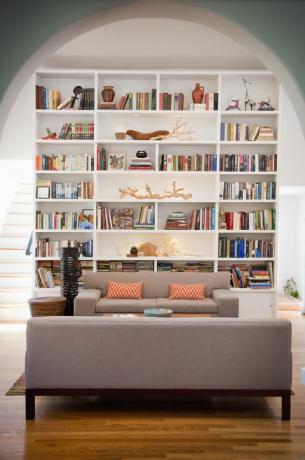Jasny salon z wysokimi półkami na książki