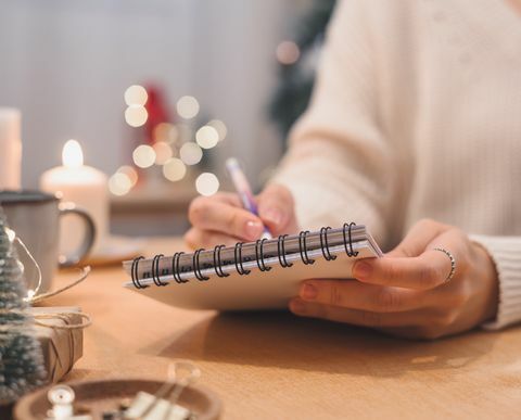 cele plany zrobić i lista życzeń na nowy rok koncepcja bożego narodzenia pisanie w notatniku kobieta ręka trzyma długopis w notatniku w domu na ferie zimowe święta