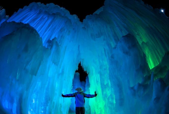 osoba stojąca w dużej jaskini lodowej