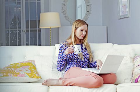 Kobieta na laptopie siedzi w swoim salonie