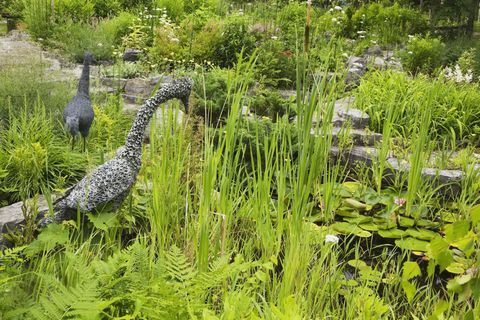 Ozdobny staw z posągami z siatki drucianej w ogrodzie krajobrazowym na podwórku na wiosnę