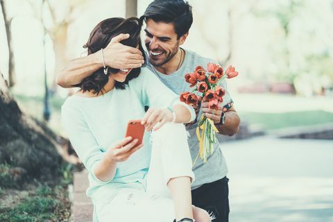 Młody człowiek zaskakuje swoją dziewczyną z bukietem tulipanów