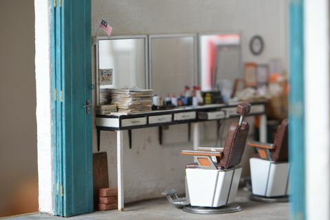 miniaturowa replika salonu fryzjerskiego z trzema lustrami, dwoma krzesłami fryzjerskimi i ladami zawierającymi przybory fryzjerskie