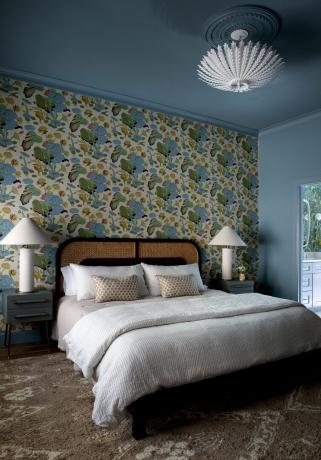 sypialnia z tapetą w kolorowe liście i symetrycznymi stolikami nocnymi