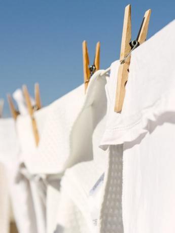 białe ubrania rozwieszone do wyschnięcia na sznurze do prania na jasnym, ciepłym, słonecznym tle to czyste, błękitne niebo
