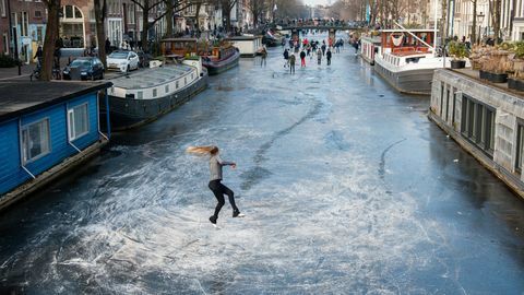 Dziesiątki ludzi jeżdżących na łyżwach po kanałach Amsterdamu