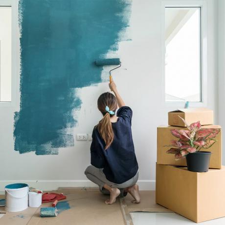 kobieta maluje ścianę na niebiesko
