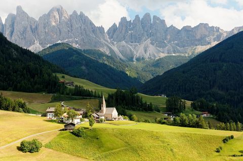 Letnia sceneria sielankowej Val di Funes z surowymi szczytami Odle (Geisler) w tle i kościołem w wiosce Santa Maddalena w zielonej trawiastej dolinie w Dolomiti, Południowy Tyrol, Włochy