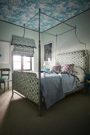 Niebieska sypialnia z tapicerką w ptasie wzory i łóżkiem z baldachimem
