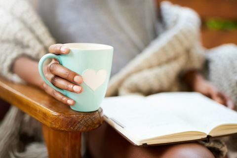 Przycięte ujęcie kobiety relaksującej z książką i filiżanką kawy