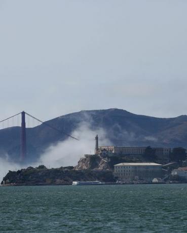 niska mgła wiruje wokół Alcatraz i mostu Golden Gate pod czystym niebem, gdy łodzie płyną po zatoce San Francisco